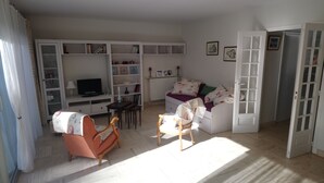 Un salon comprenant un canapé, un téléviseur, une bibliothèque et une table à manger.