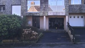 Un immeuble résidentiel à deux étages, doté d’un toit en pente, d’une entrée principale et d’un garage apparent.