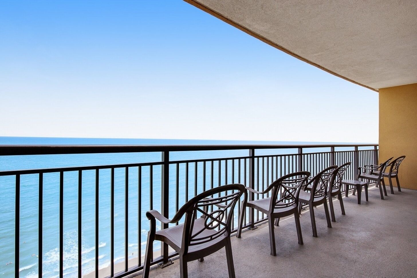 A balcony with chairs overlooking the sea.