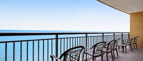 A balcony with chairs overlooking the sea.