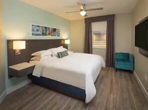 Relax in comfort with a large bed, nightstand, and wall-mounted TV.