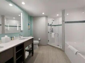 Bathroom features a large mirror, vanity, and shower area with a glass door.