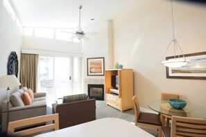 Une chambre d’hôtel équipée d’un canapé, d’une table à manger avec des chaises, d’une télévision, d’une cheminée et d’un ventilateur de plafond.