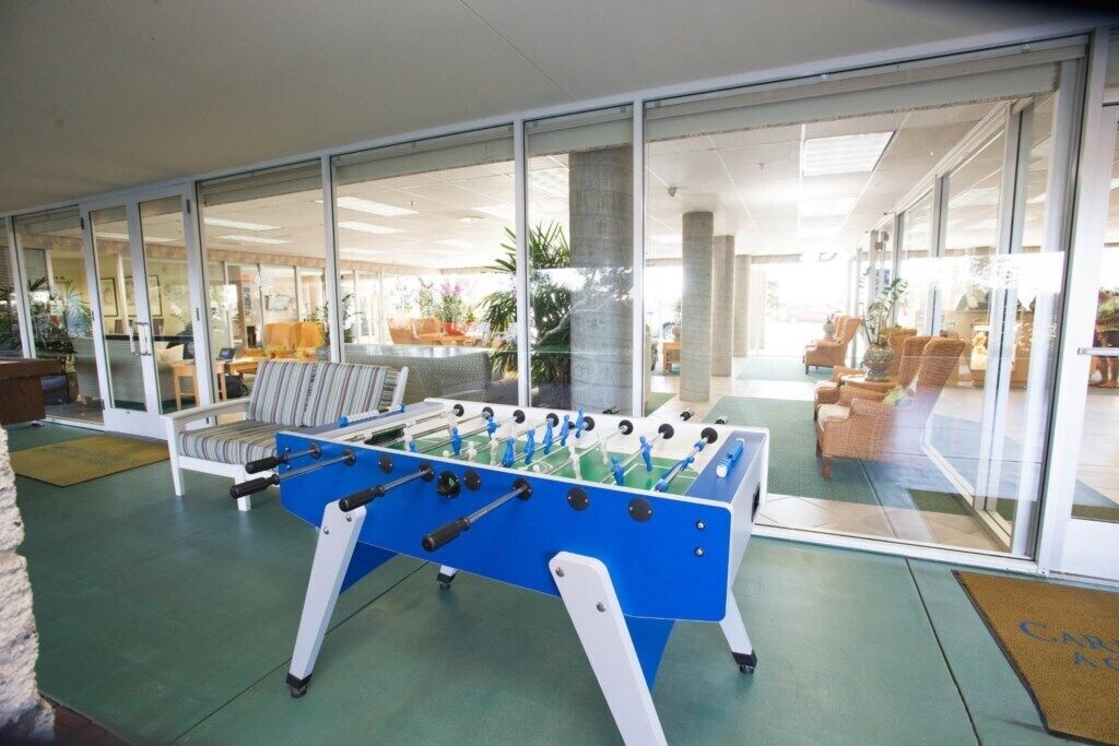 A foosball table in a bright room with large windows and a view of the outside.