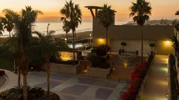 Un resort con piscina, palme e vista sulla spiaggia al tramonto.
