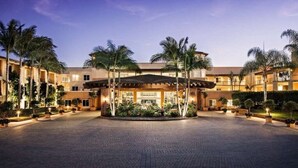 A hotel with a central courtyard, palm trees, and a covered entrance.