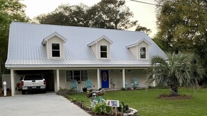 Une maison à deux étages avec une porte d’entrée bleue, un porche couvert et un camion garé devant.