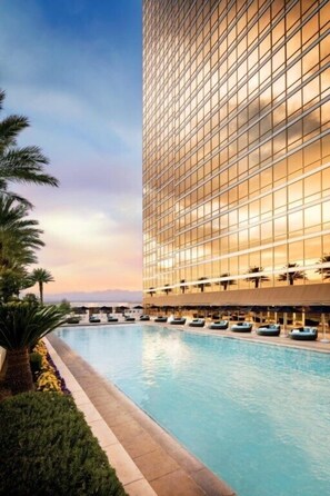 Relax by the pool surrounded by lush greenery and lounge chairs.