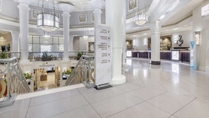 A spacious hotel lobby with a central staircase, a fitness center, and a business center.