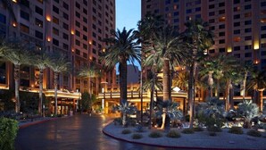 A hotel with multiple high-rise buildings, palm trees, and a well-lit entrance area.