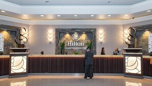 Un'area reception con un cartello del 'Hilton Grand Vacations Club', una scrivania e due applique decorative.