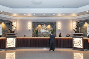 A reception area with a 'Hilton Grand Vacations Club' sign, a reception desk, and two decorative wall sconces. - Las Vegas | Pool & Strip Access | 3BR Sleeps 8 (Las Vegas)