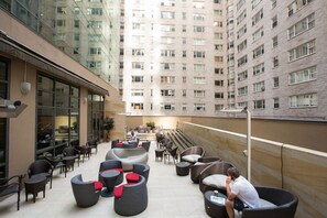 A rooftop patio with outdoor seating, a view of a high-rise building, and a clear sky. - West 57th Street, a Hilton Club - 1 - Bedroom - 1 BD (New York)