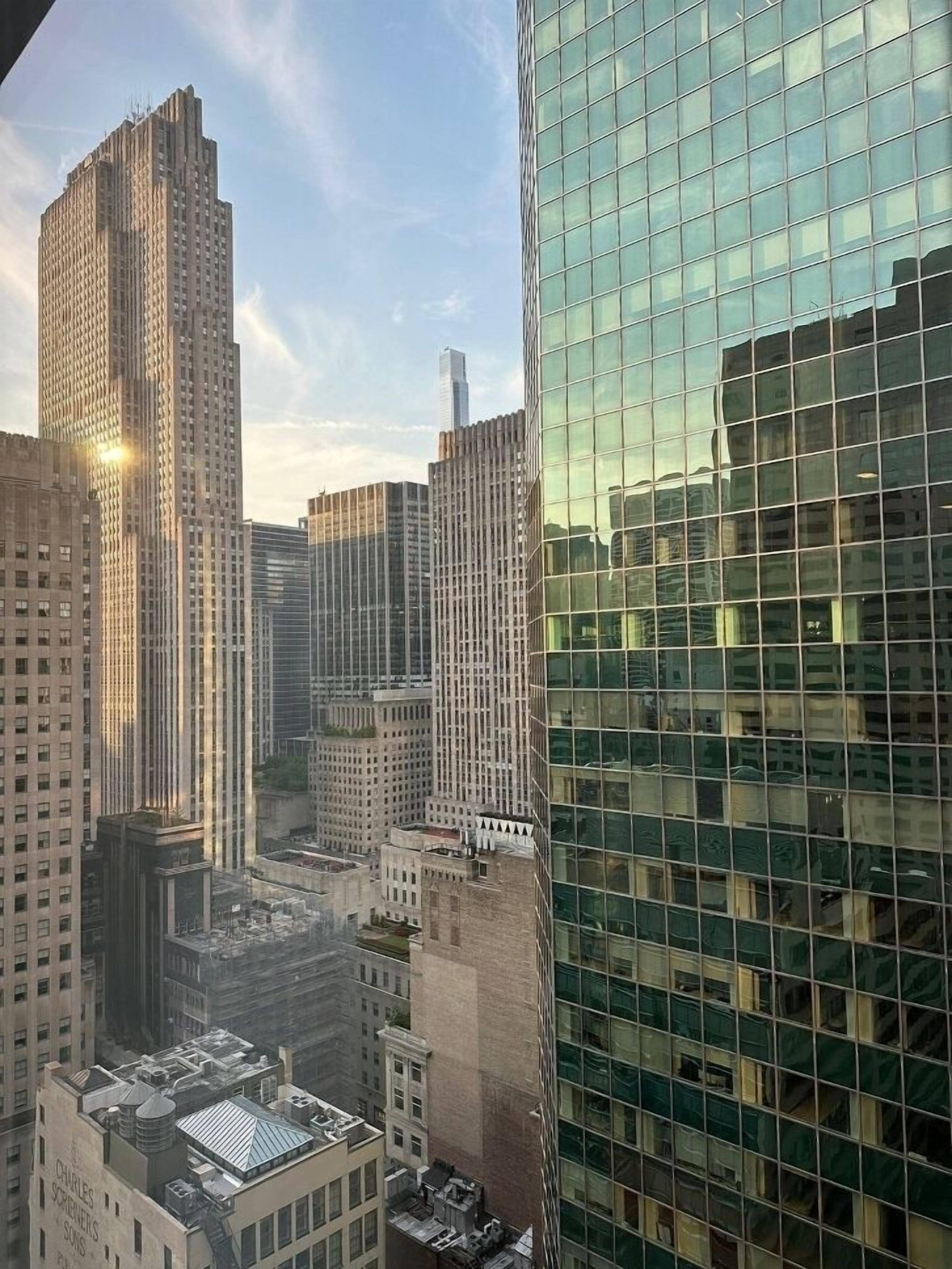 A cityscape with high-rise buildings, including a prominent glass skyscraper reflecting the sky.