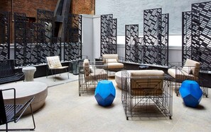 A modern lounge area with metal-framed seating, a round table, and a geometric blue accent piece. - NYC | 5th Ave Location | Central Park | Studio (New York)