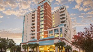 A multi-story hotel with a central tower, balconies, and a well-lit entrance.