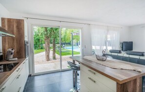 Une cuisine moderne dotée d’une grande porte-fenêtre coulissante qui donne sur un jardin.