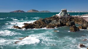 A coastal scene with rocky outcrops and a clear view of the sea.