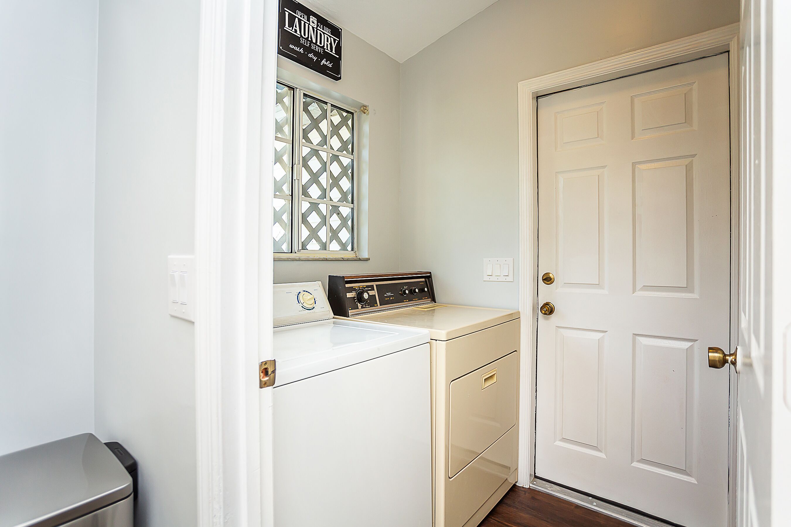 A laundry room with a washing machine, a dryer, and a self-serve sign.