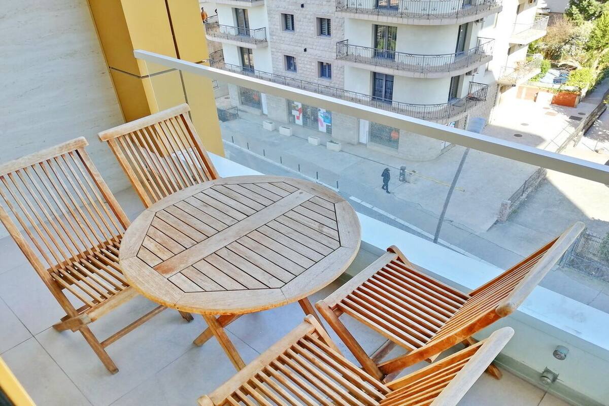 A balcony with a round wooden table and four wooden chairs.