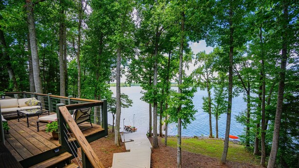 Une terrasse en bois avec des sièges extérieurs et une vue sur un lac.