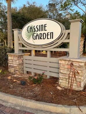 Welcome to Cassine Garden, a serene oasis with a circular sign featuring a palm leaf motif.