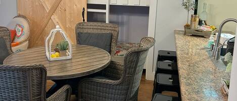 A dining area with wicker chairs, a round table, and a chandelier.