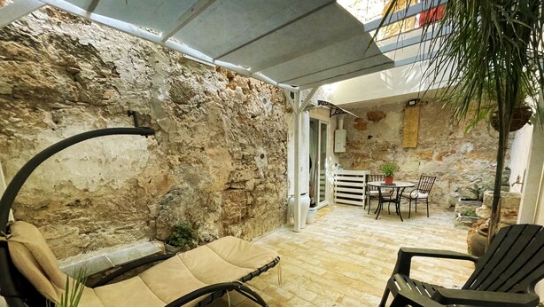 A cozy outdoor seating area with a stone wall, a covered patio, and a view of the interior. - Tufoletto Apartment (Palermo)