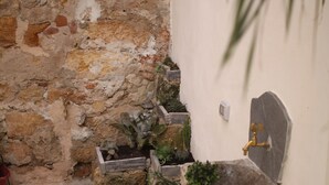 A narrow stone pathway leading to a rustic stone wall with a small garden area. - Tufoletto Apartment (Palermo)