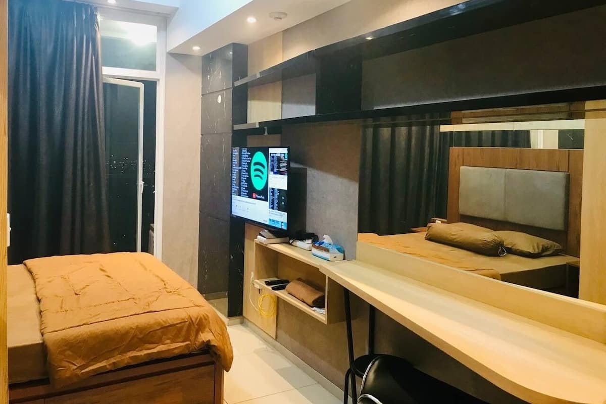 Ein modernes Hotelzimmer mit Bett, Schreibtisch und Fernseher.