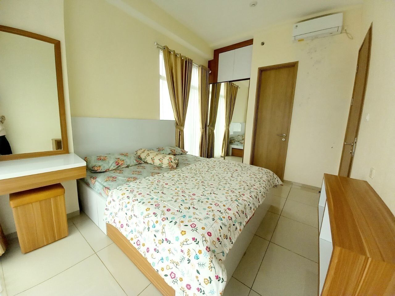 A bedroom with a bed, a desk, a mirror, and a wardrobe.