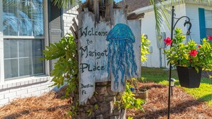 A wooden sign with a blue jellyfish and text welcoming to Marigot Place, Destin FL.