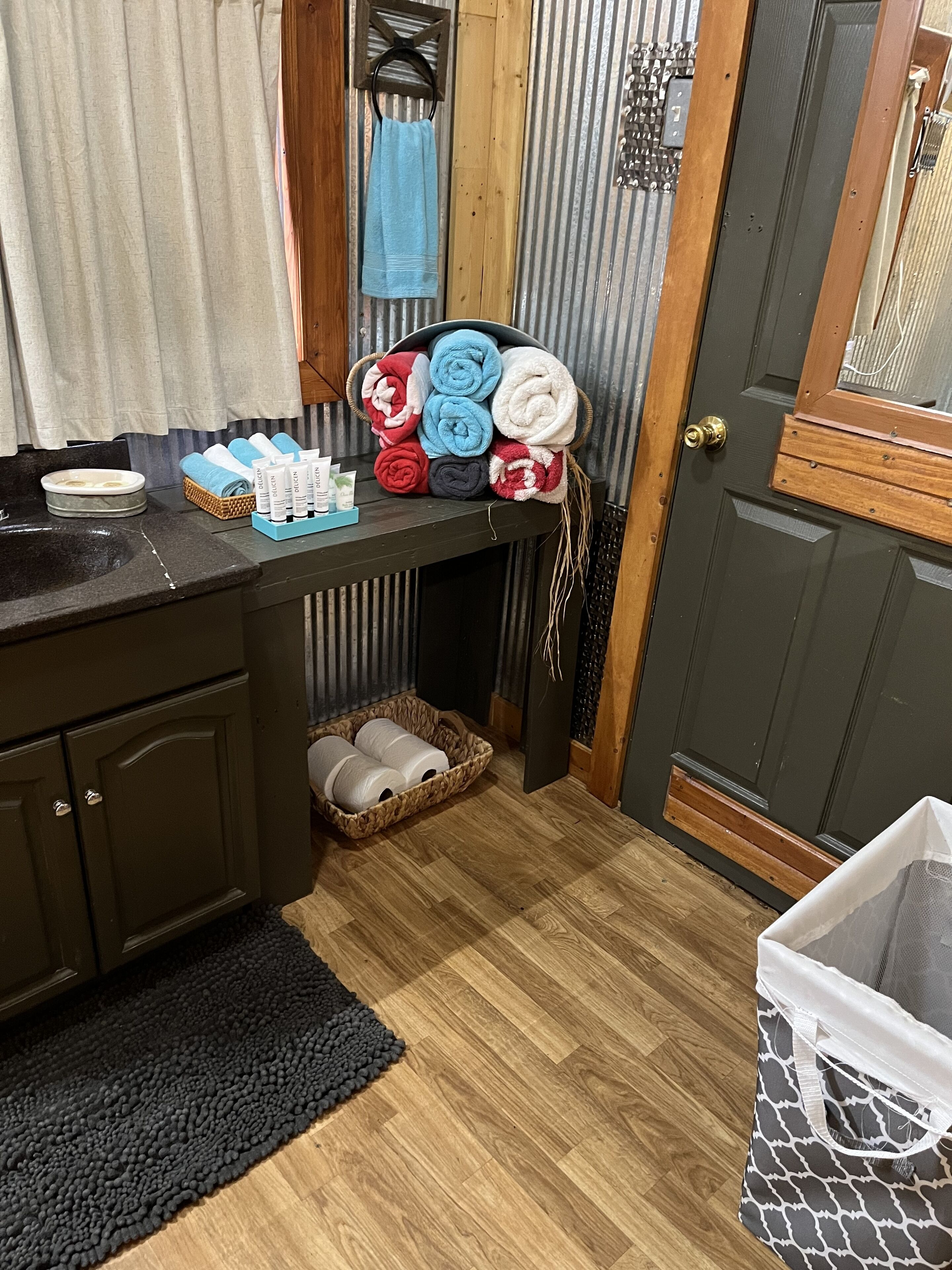 A bathroom with a wooden vanity, a sink, and a towel rack with neatly folded towels.