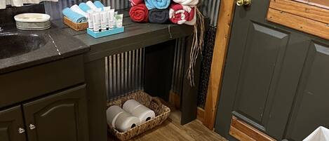 A bathroom with a wooden vanity, a sink, and a towel rack with neatly folded towels.