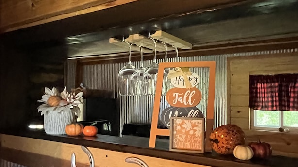 Een houten toonbank met een rustieke uitstraling, met een bord waarop staat 'Happy Fall' en een decoratieve pompoen.