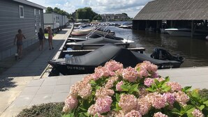 A marina with boats docked, a covered boat house, and a row of houses along the water.