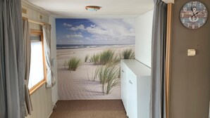 A room with a beach mural, a clock, and a radiator.