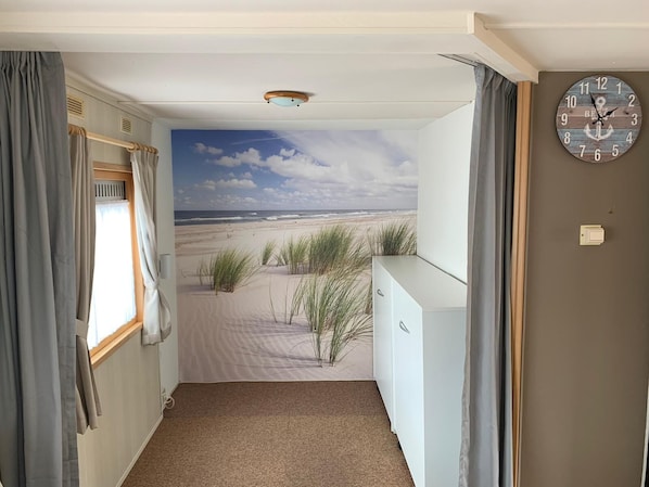 Habitación con un mural de playa, un reloj y un radiador.