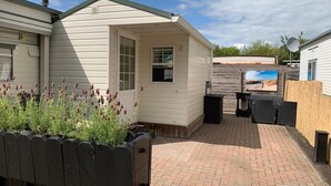 A mobile home with a patio area, a small garden with lavender, and a satellite dish.