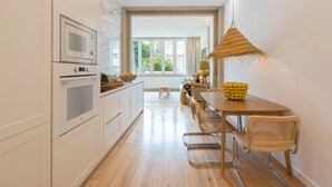 Eine moderne Küche mit weißen Schränken, einem Holztisch und einer Pendelleuchte.