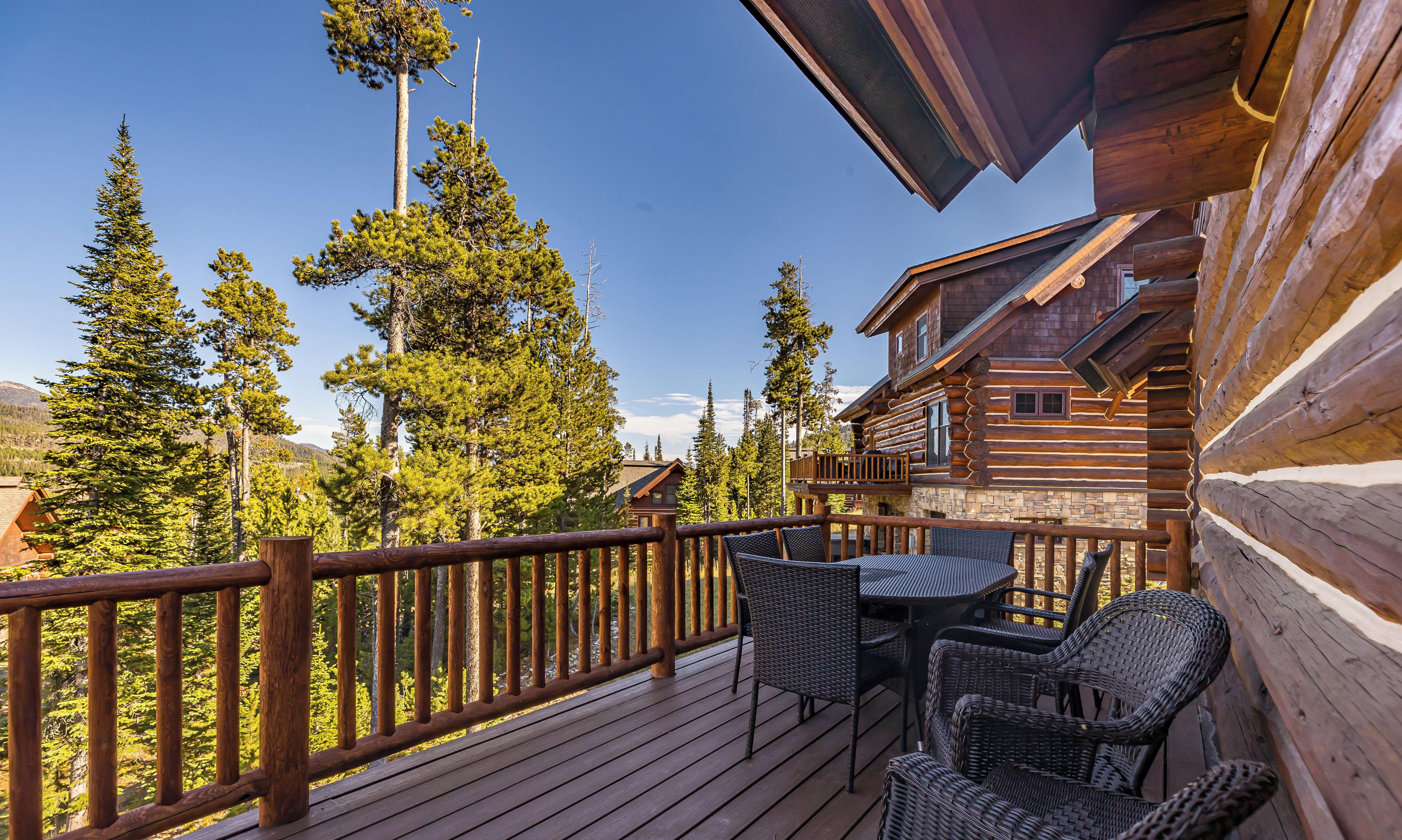 A wooden deck with wicker furniture, overlooking a forested area.