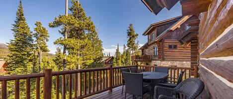 A wooden deck with wicker furniture, overlooking a forested area.