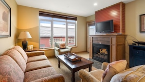 A living room with a fireplace, sofa, and television. - Amazing Unit!  Sleeps 5. Swim or Ski out your front door. On site at Silver Mt. (Kellogg)