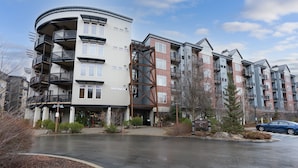 A multi-story residential building with balconies, a central entrance, and a parking area. - Amazing Unit!  Sleeps 5. Swim or Ski out your front door. On site at Silver Mt. (Kellogg)