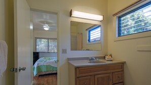 A bathroom with a wooden vanity, a mirror, and a window with blinds. - Condo 500 Feet to the Ocean (Koloa)