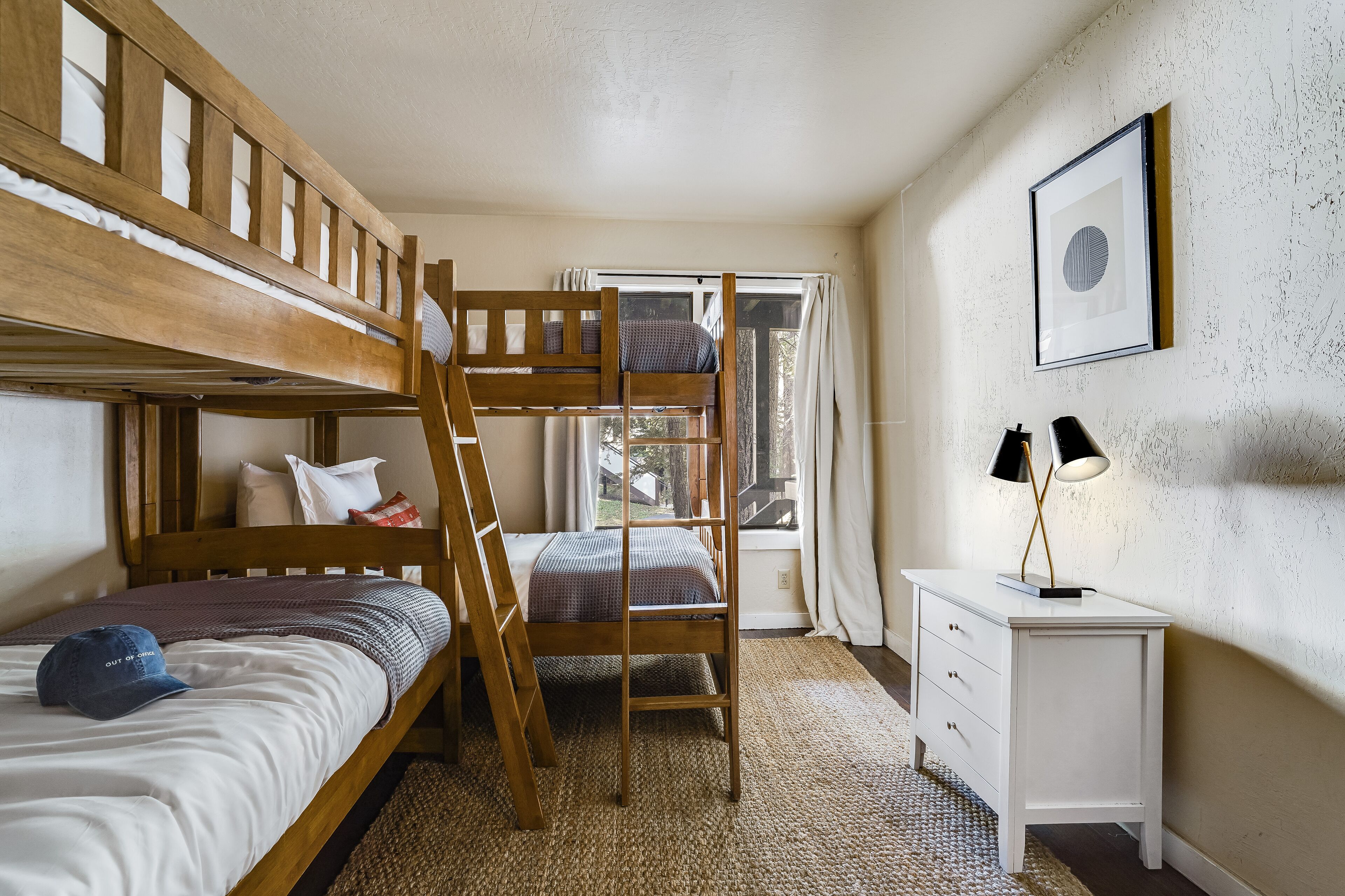 A bunk bed room with a desk and a window.