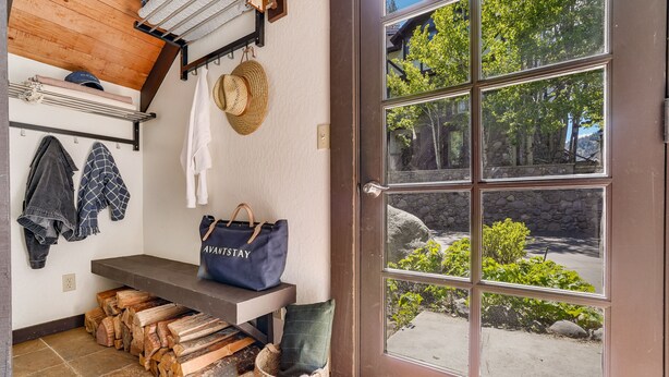 A wooden bench with a blue bag, a hat, and stacked firewood.