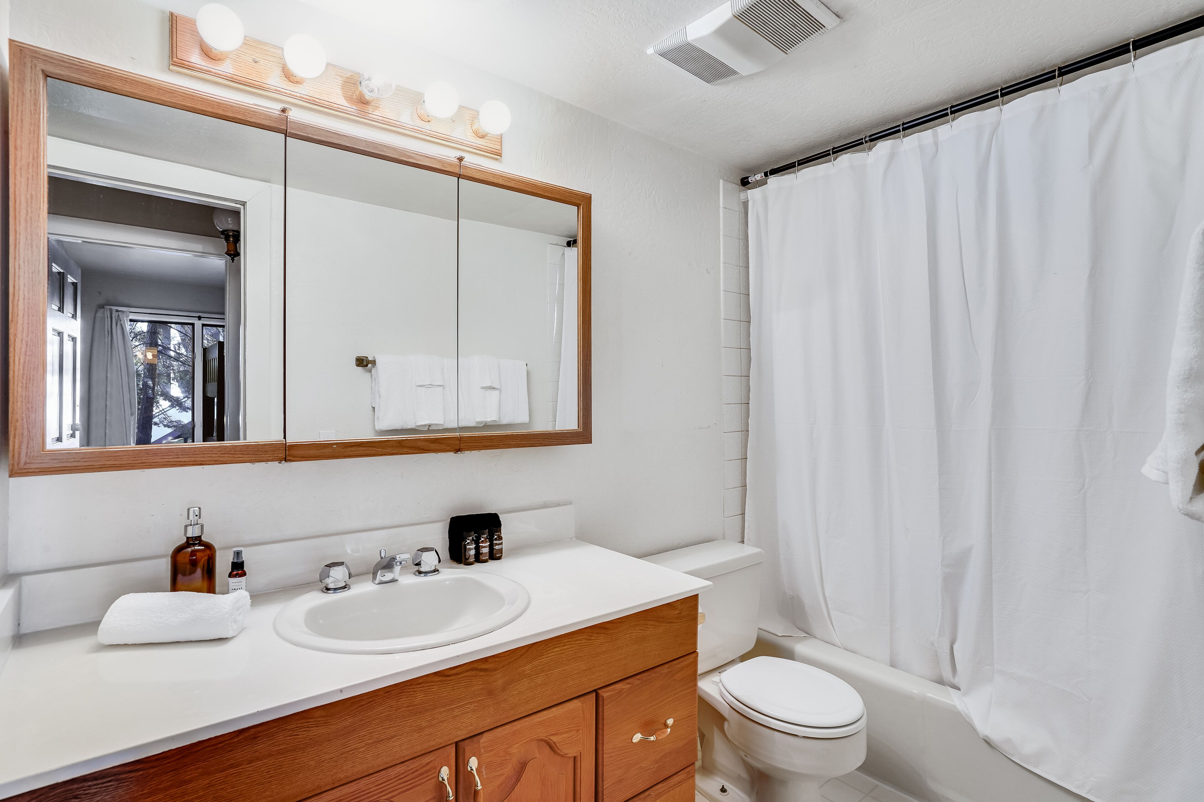 Un baño con lavamanos, espejo y retrete blancos.