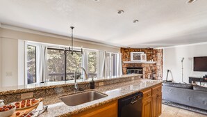 A modern kitchen with granite countertops, a dishwasher, and a stone backsplash.