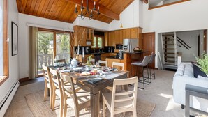 Une cuisine spacieuse avec des meubles en bois, un coin repas avec une table pour quatre personnes, et un escalier menant à l’étage supérieur.